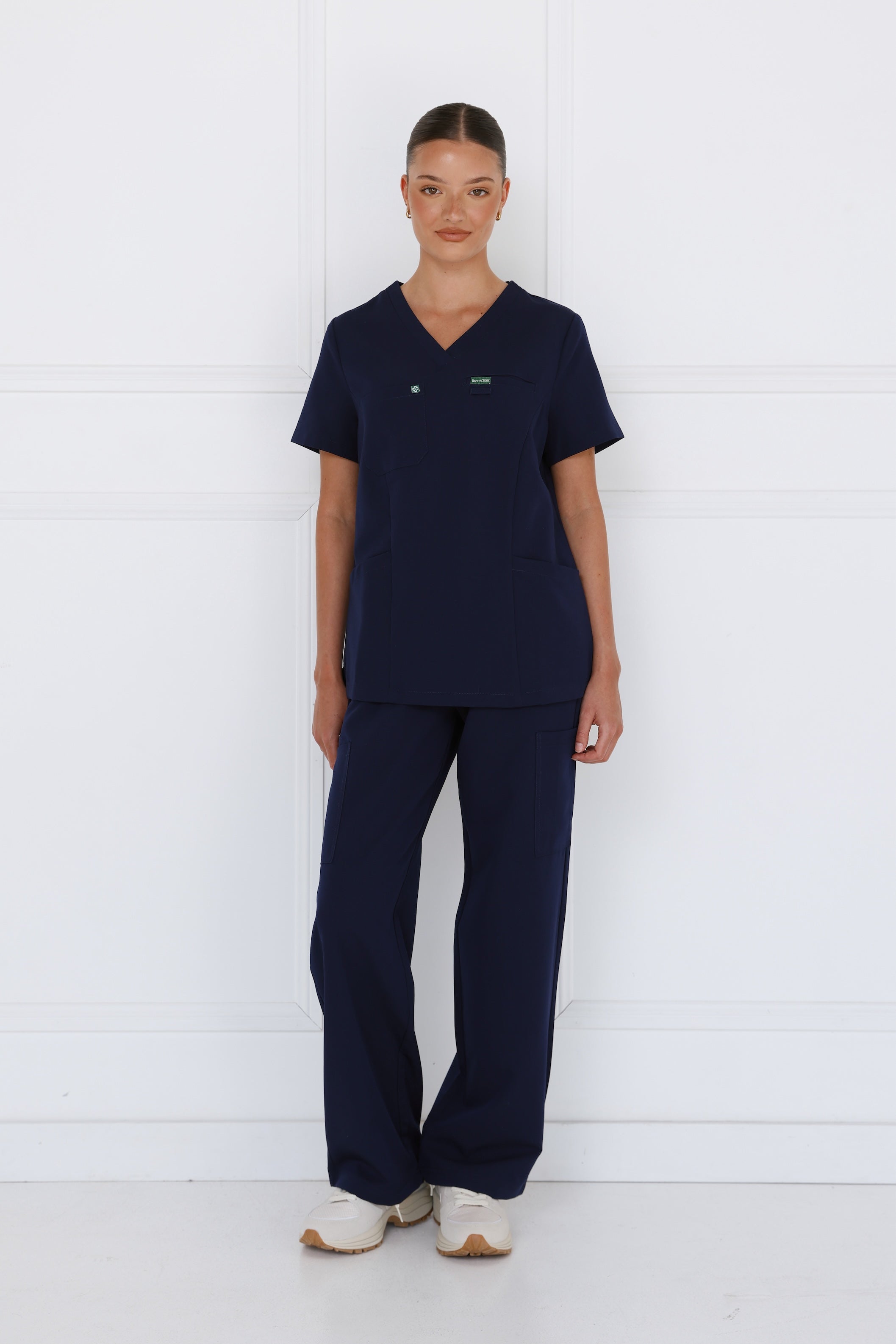 Front view of the Hero Scrubs Midnight Navy scrub set on a female model showing the deep navy blue colour, tailored fit and matching scrub pants.