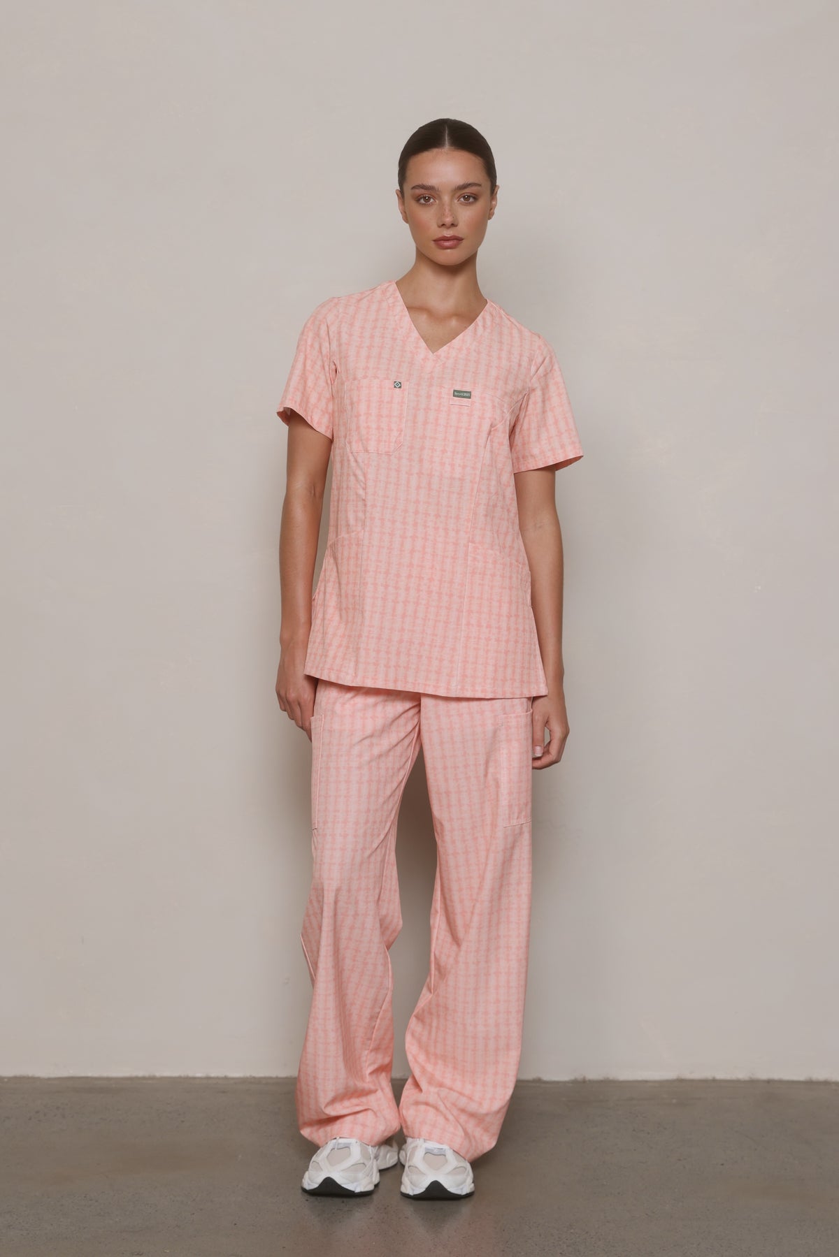 Model facing forward in a Hero Scrubs Peach Relaxed Back V-neck top and matching pants.