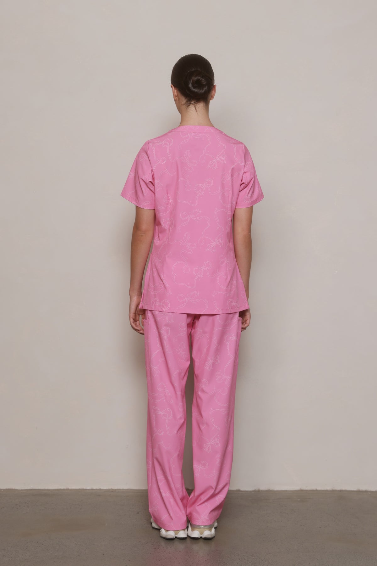 Back view of a model wearing a Hero Scrubs pink printed top and matching pants.