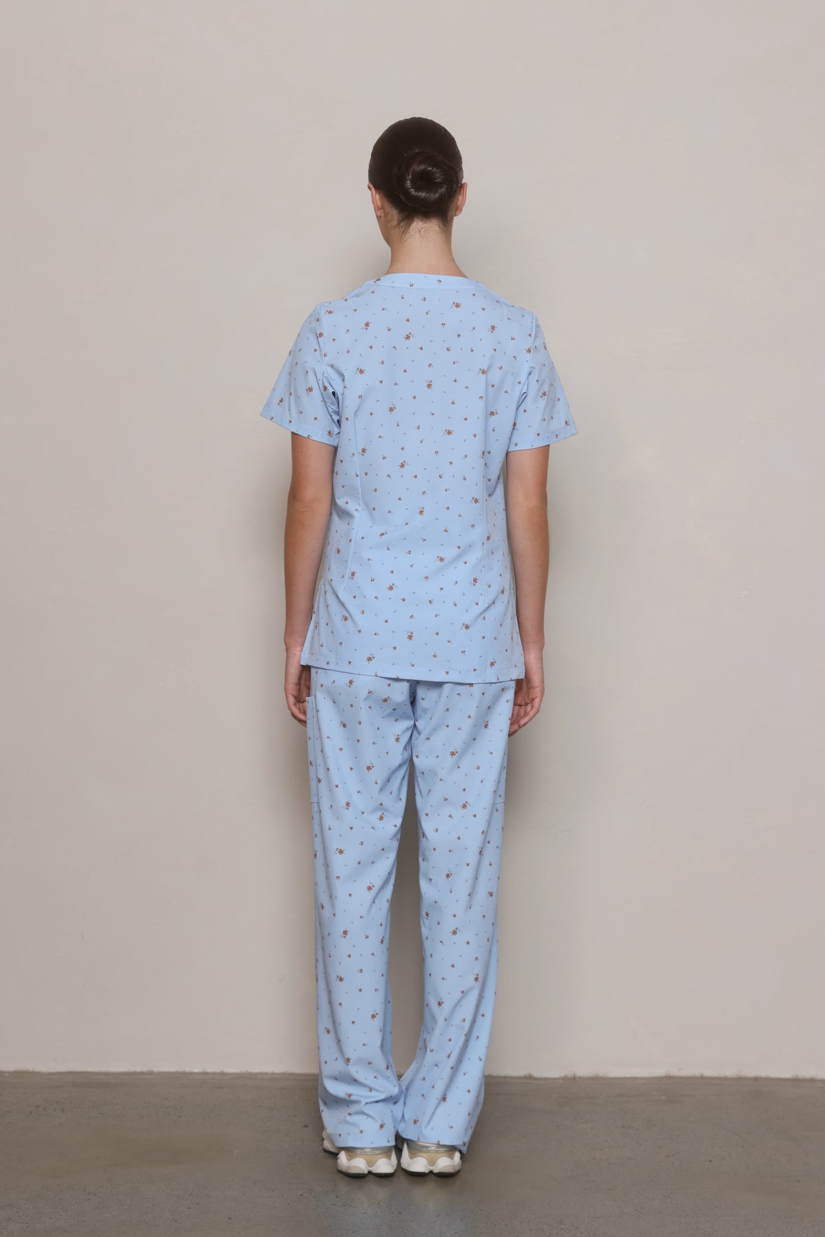 Back view of a model wearing a Hero Scrubs powder blue scrub set.
