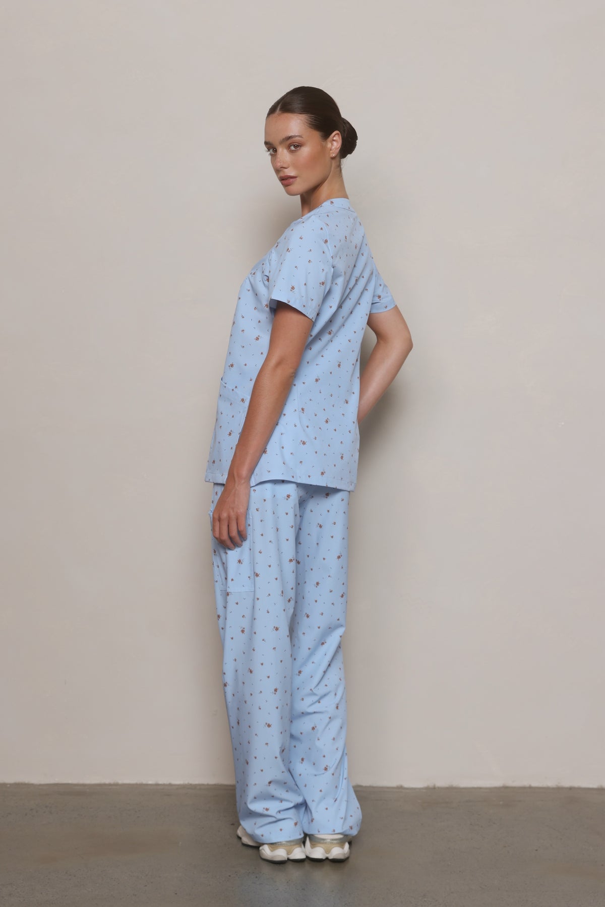 Side view of a model wearing a Hero Scrubs powder blue scrub set.
