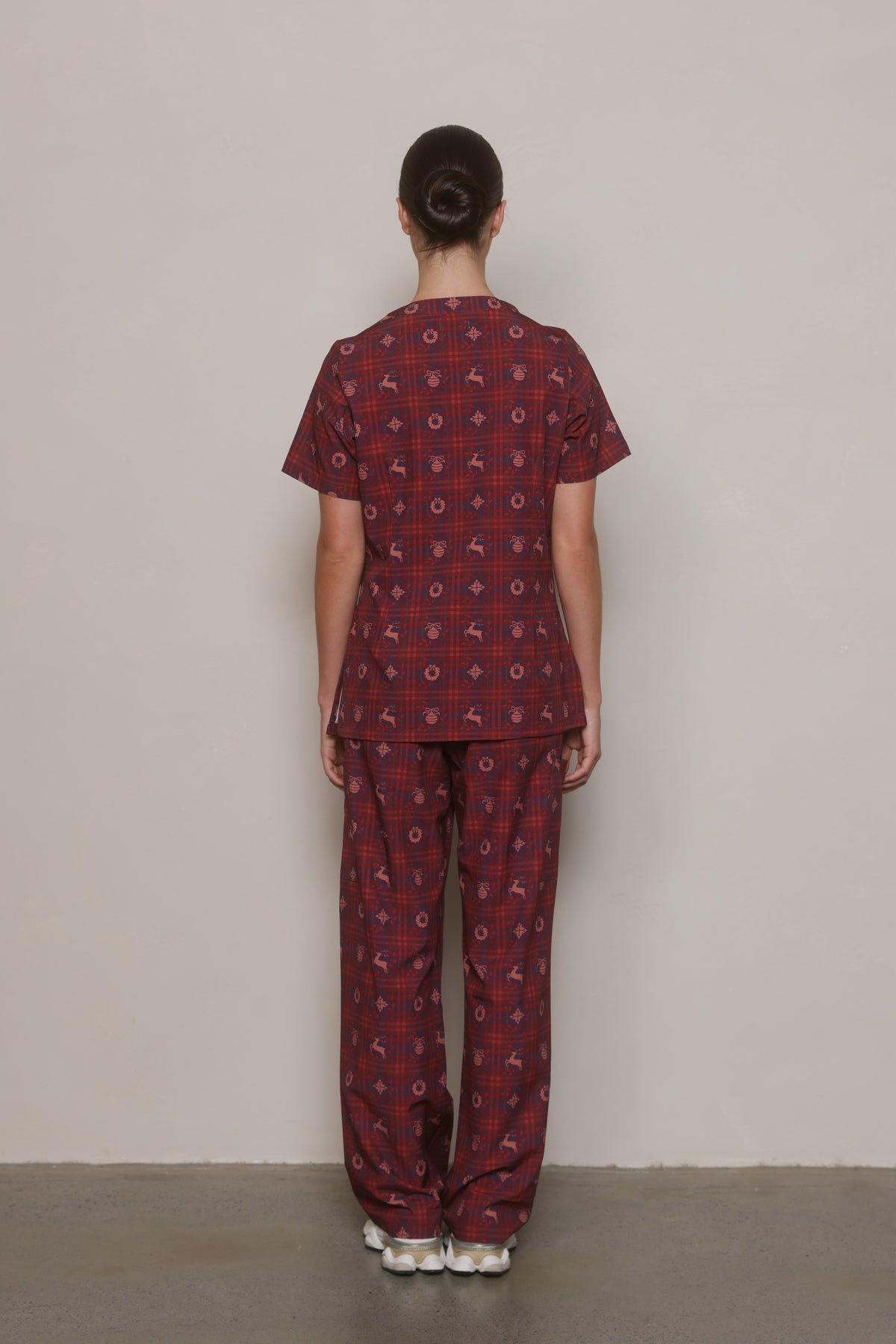 Back view of a burgundy Christmas-print Hero Scrubs top and matching pants on a model.