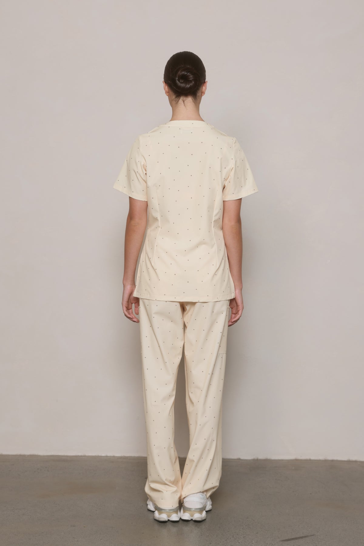 Back view of a model wearing a Hero Scrubs cream printed top and matching pants.