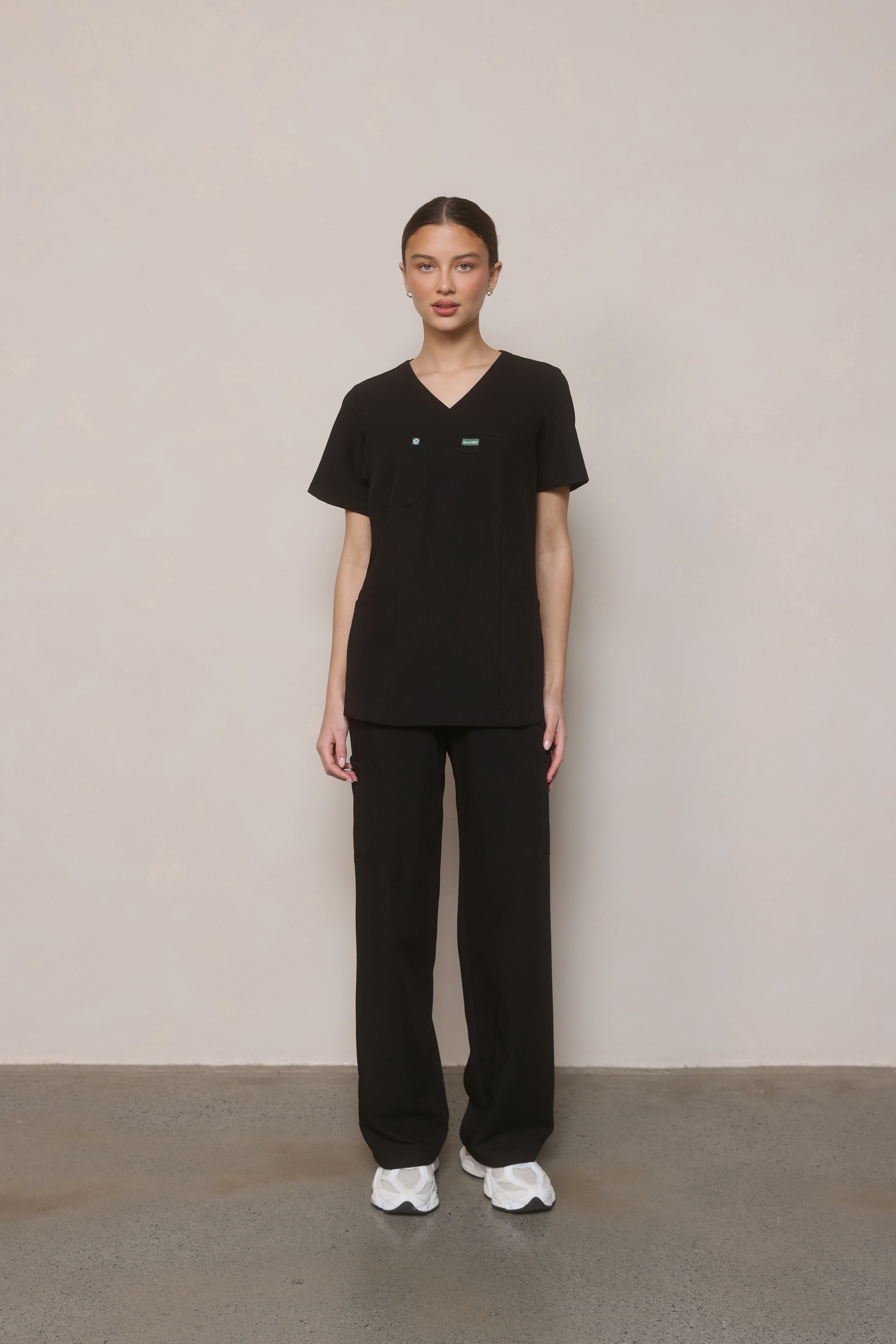 Model standing front-on wearing Hero Scrubs Black scrub top and pants