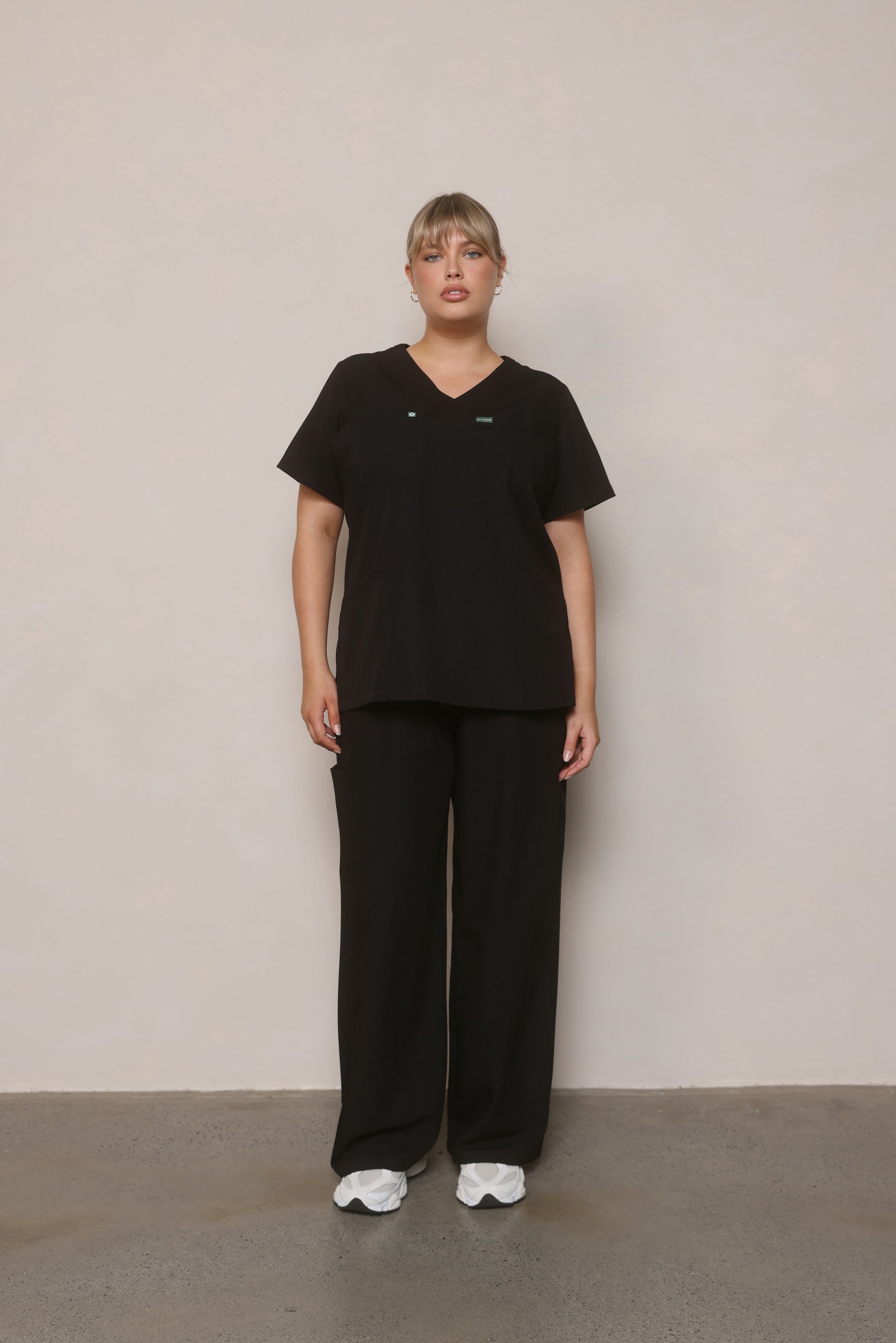 Model standing front-on wearing Hero Scrubs Black women’s scrub set