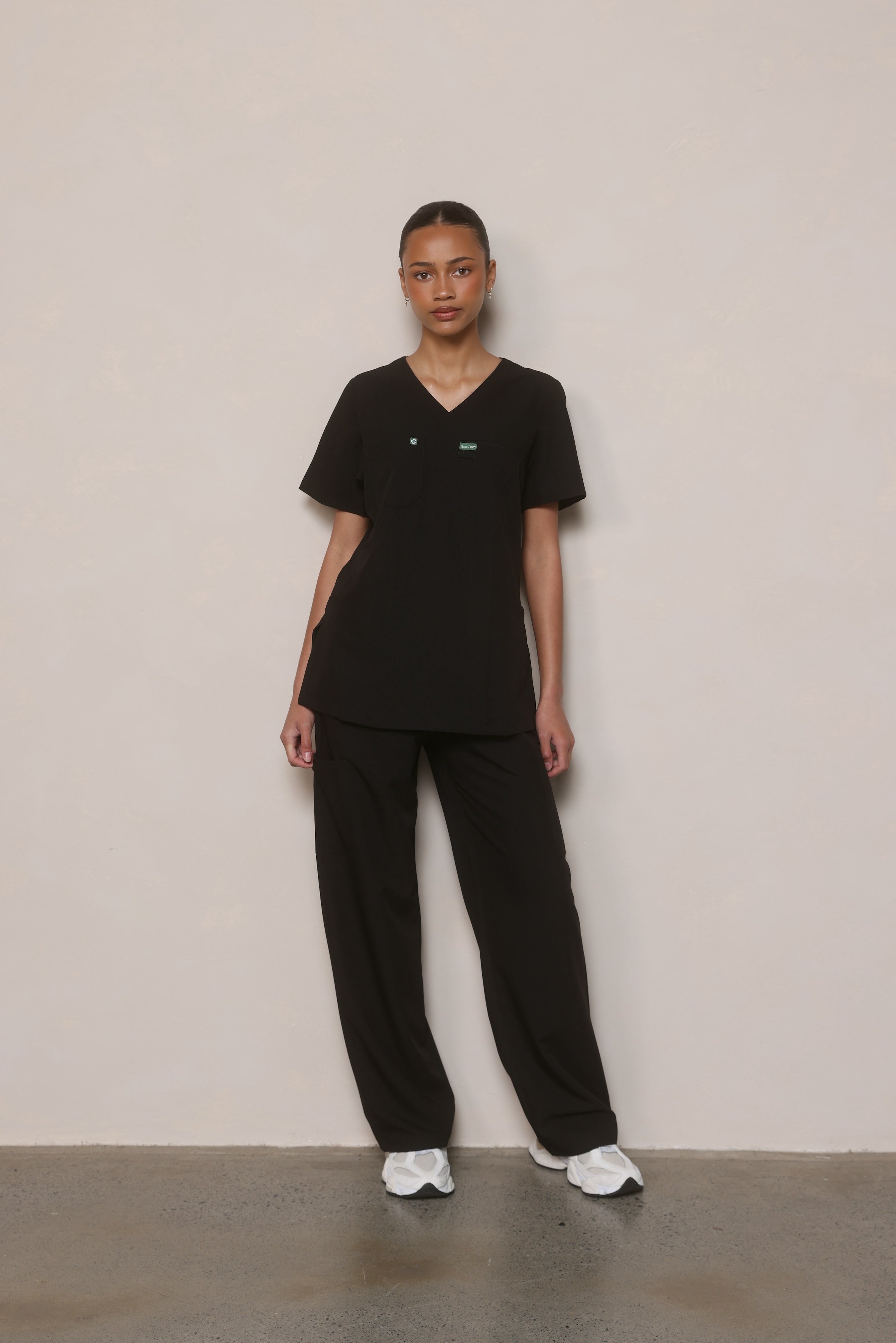Model wearing Hero Scrubs Black women’s scrub set in a relaxed front pose