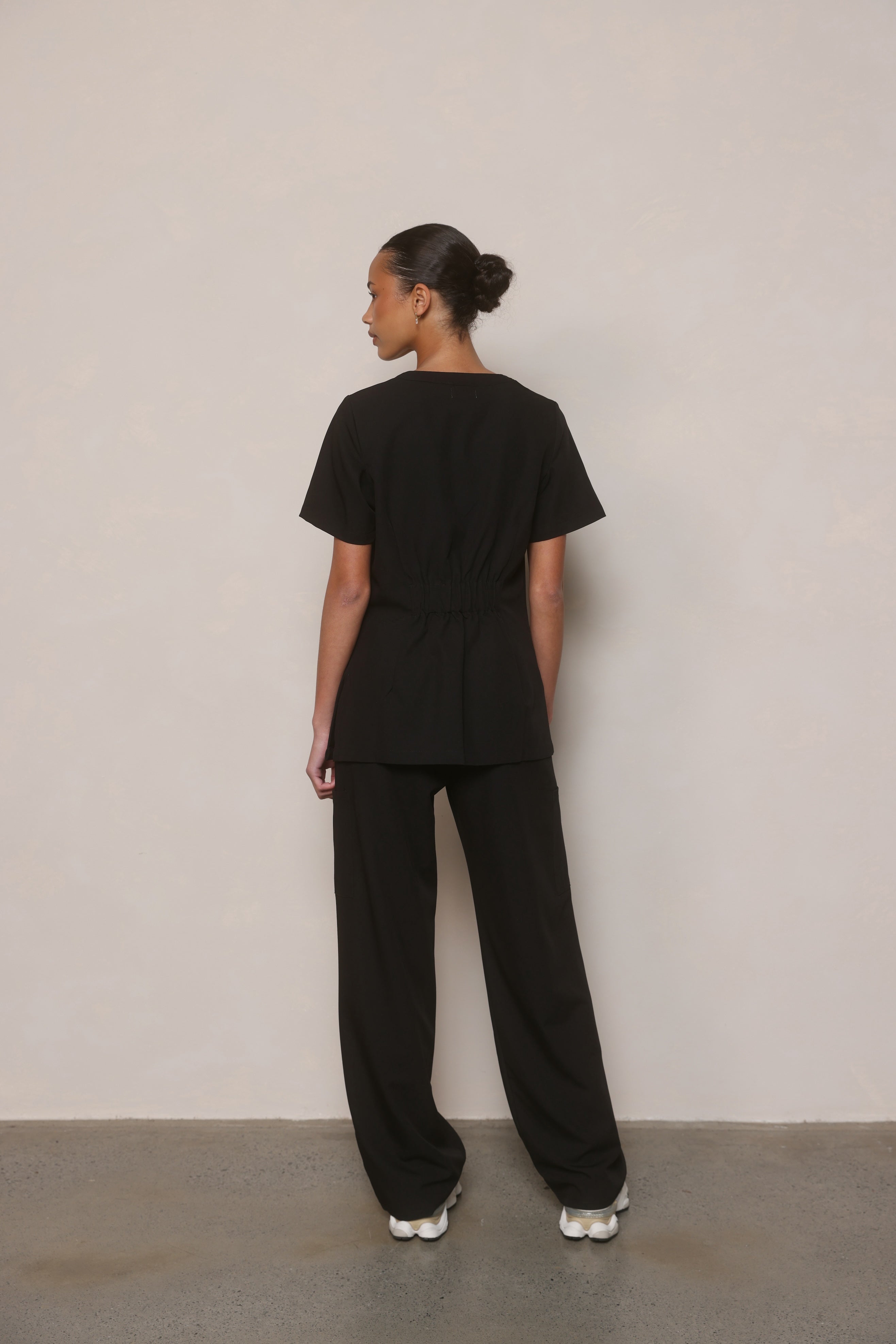 Model turned to show the back and side of Hero Scrubs Black women’s scrub set