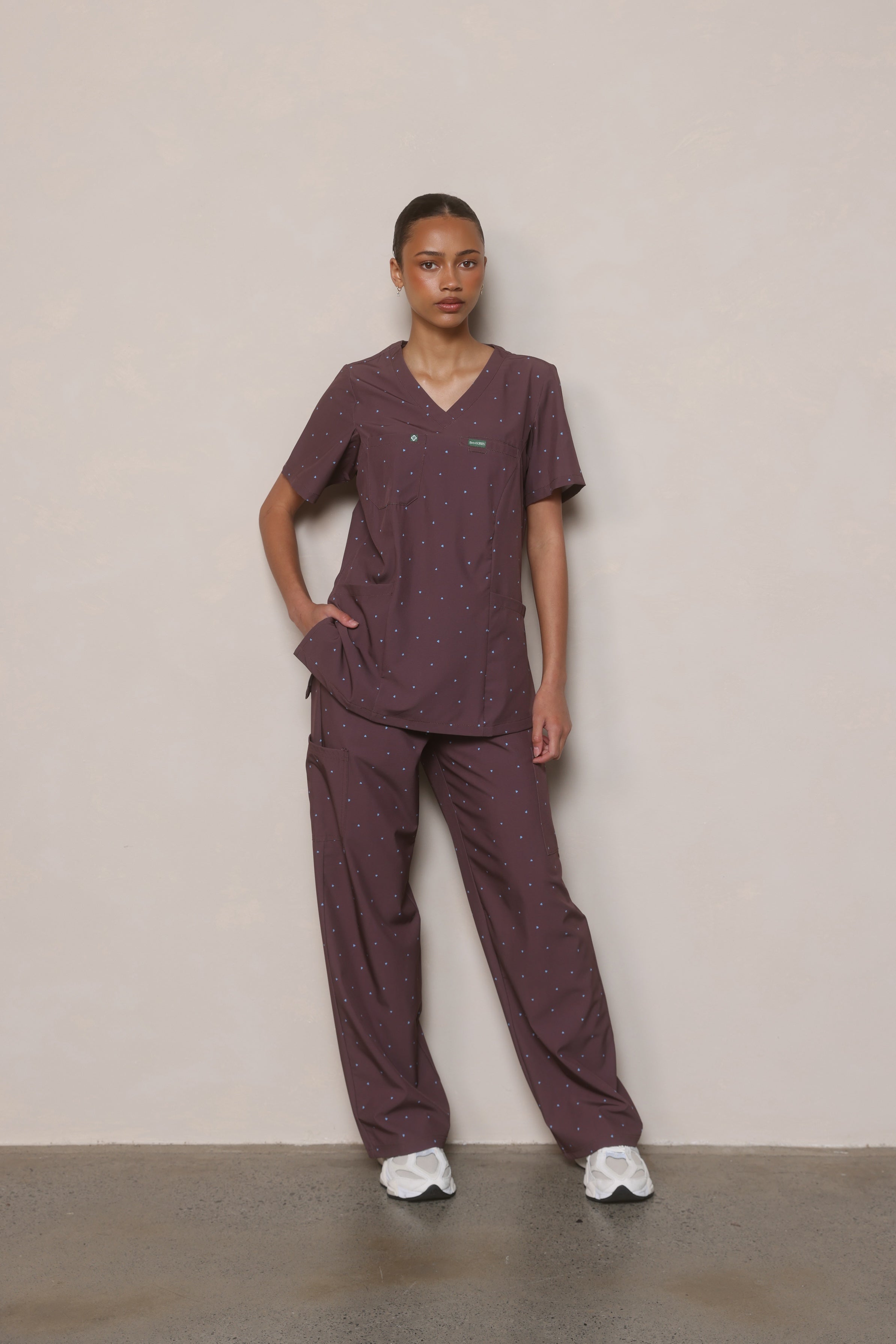 Front shot of a model wearing the XS cocoa heart scrub set by Hero Scrubs