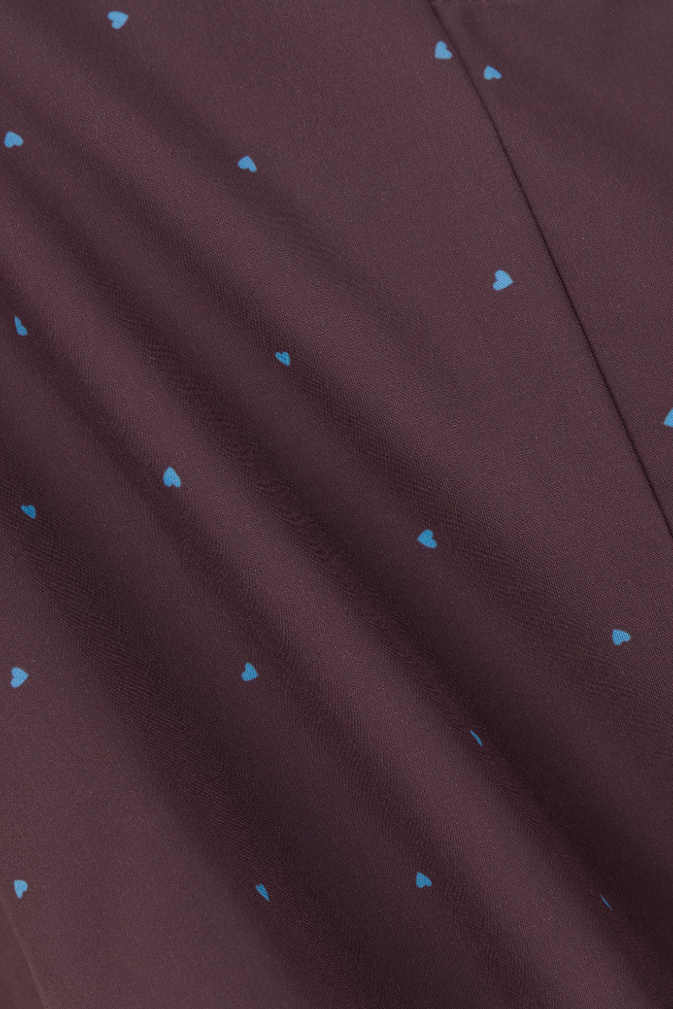 Close-up of Cocoa Hearts chocolate brown scrub fabric with blue micro heart print