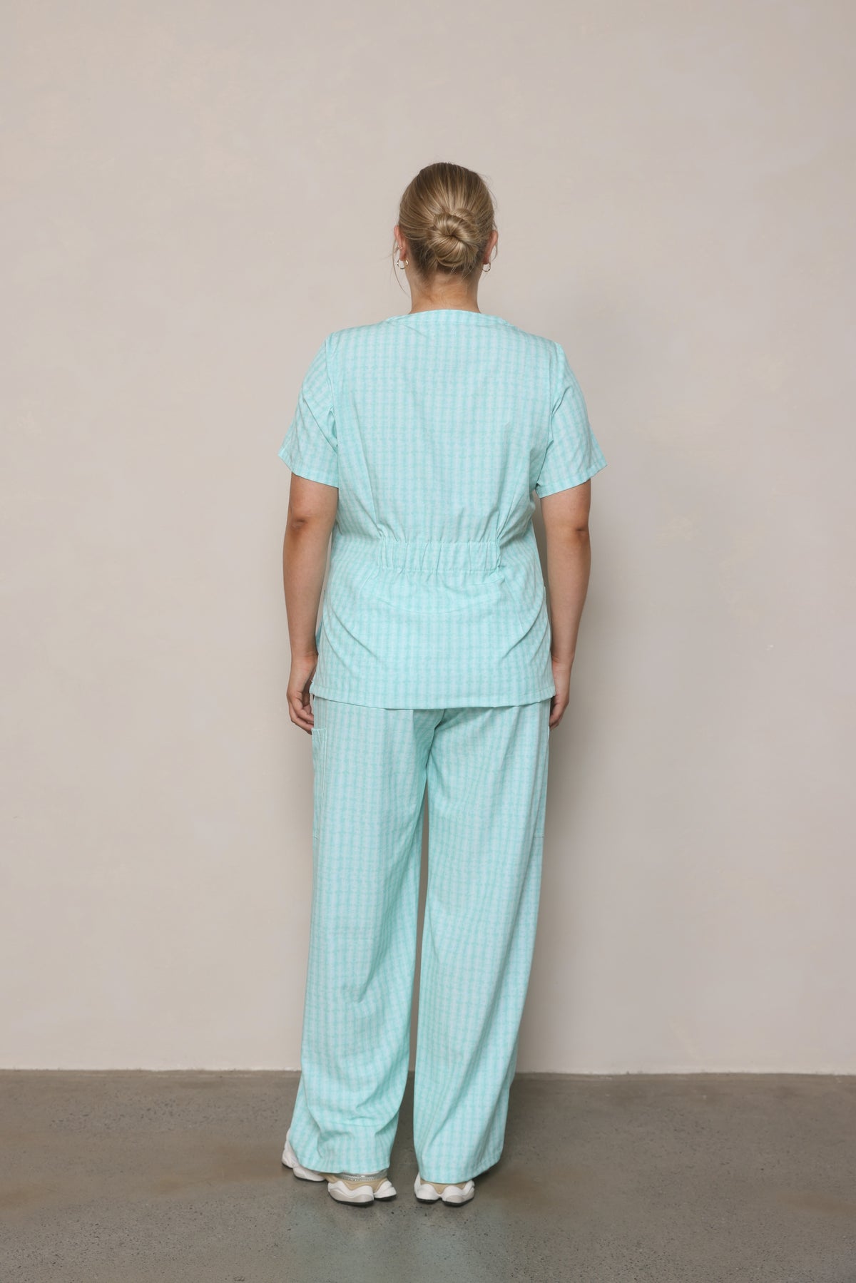 Model standing back-on wearing Hero Scrubs Mint women’s scrub set