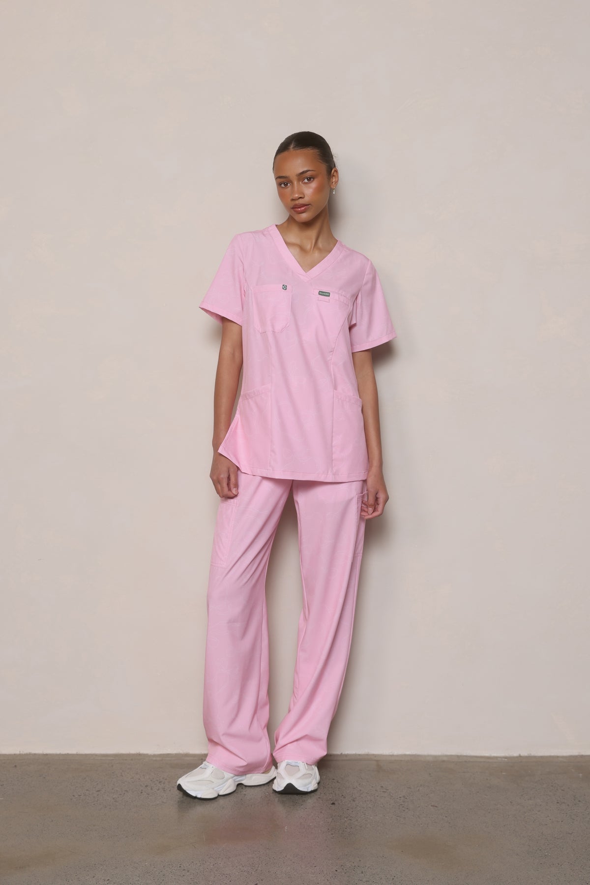 Model wearing Hero Scrubs Pink scrub set in a relaxed front pose