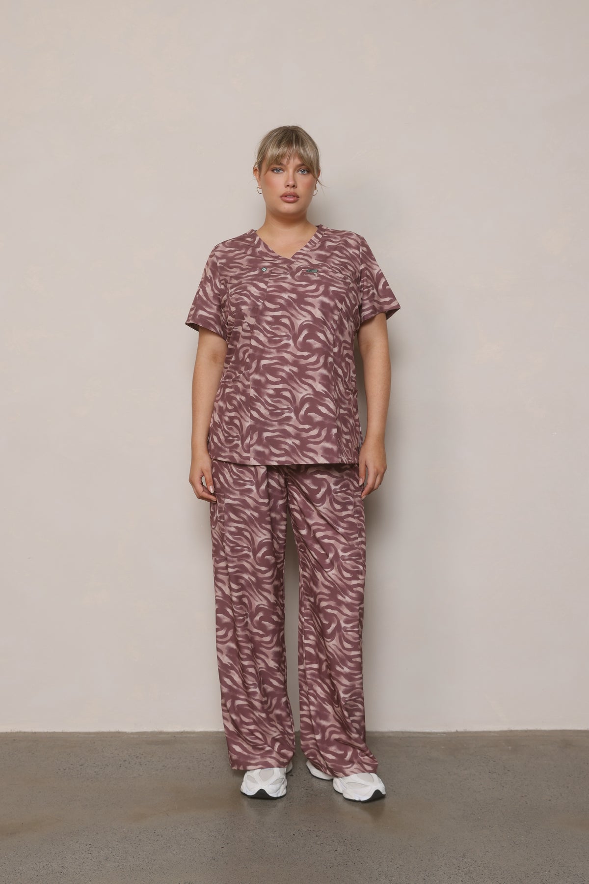 Model standing front-on wearing Hero Scrubs Zebra women’s scrub set