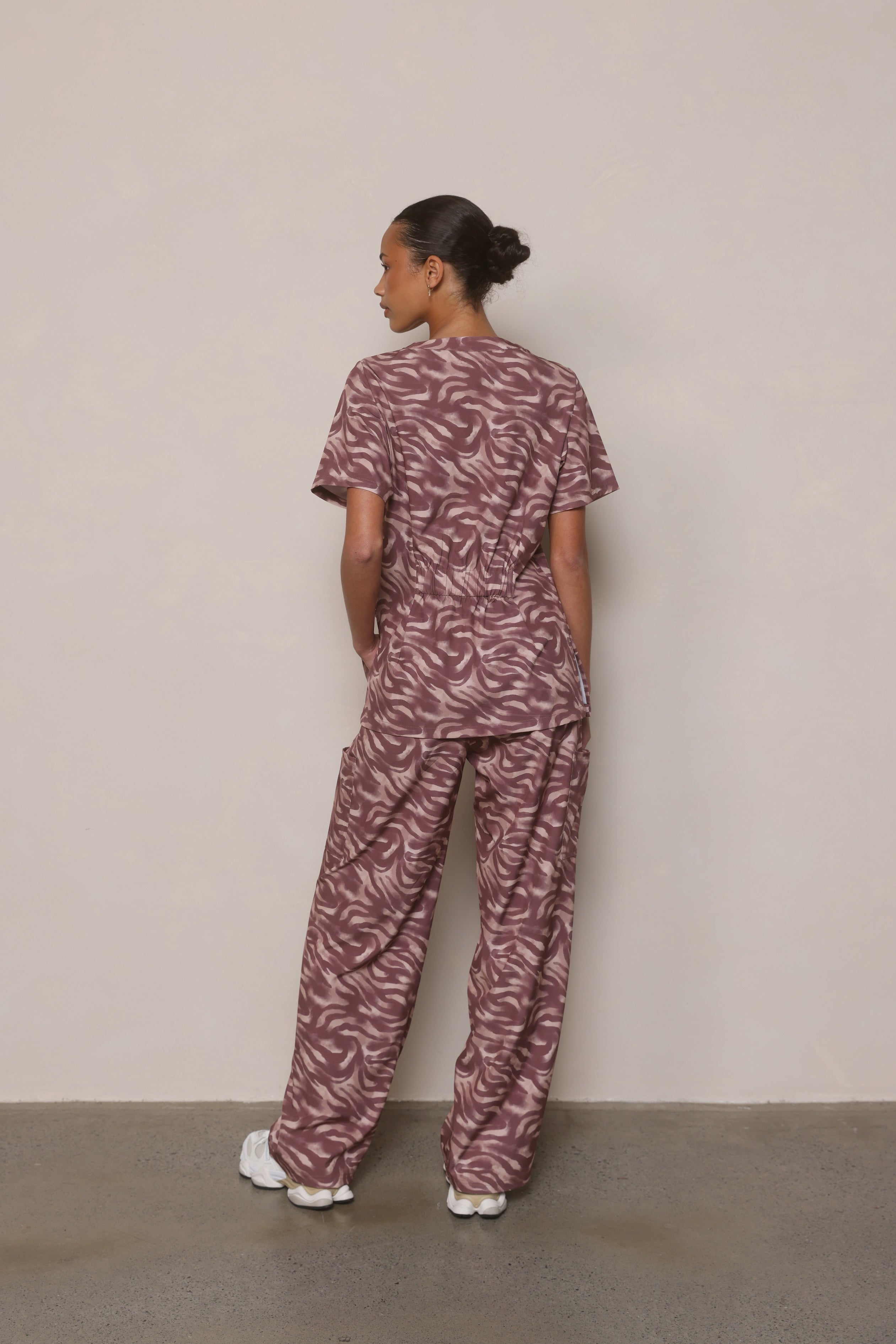 Model wearing Hero Scrubs Zebra women’s scrub set in a turned pose